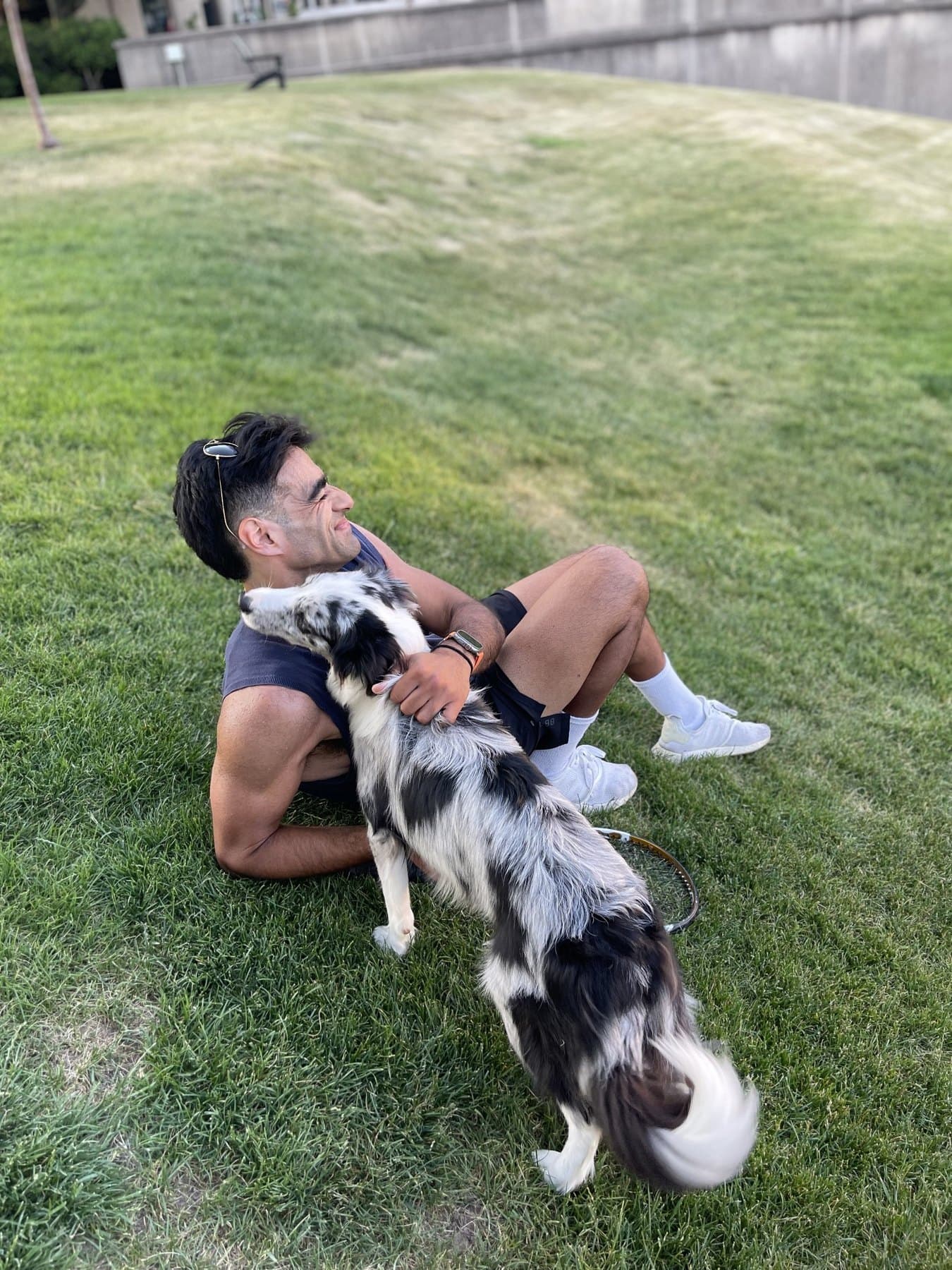 Arjan Singh Puniani relaxing on grass with a dog